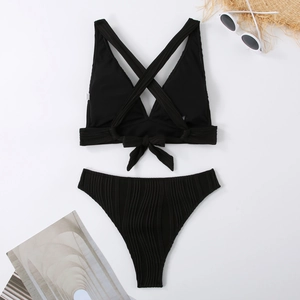 Flat lay of black ribbed bikini set with lace-up back design and stylish vacation props