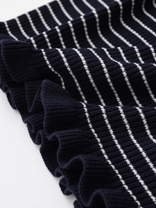 Gros plan sur un tricot côtelé bleu marine à rayures blanches et volants élégants