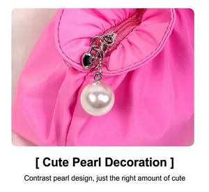 Dettaglio del beauty case rosa impermeabile con ciondolo a perla e cuore metallico