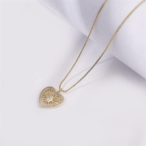 Collana con ciondolo a cuore dorato con ritratto a rilievo e zirconi su sfondo bianco