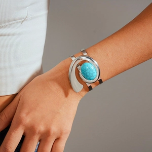 Detailed view of a silver-tone cuff bracelet featuring an oval blue turquoise stone inlay