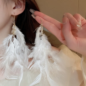 Detail of bohemian white feather tassel earrings with beads on a golden hook