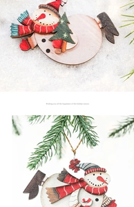 Detail of wooden snowman ornament with red accents hanging on festive pine branches