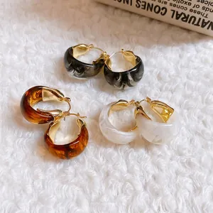 U-shaped resin hoop earrings in marble, amber, and cream white with gold clasps