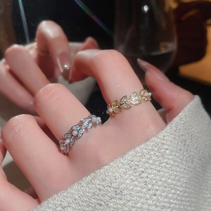 Macro detail of leaf-shaped rings with white pearls and sparkling zircons on fingers