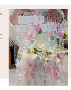 Detail of hand-knitted flower bouquet in transparent bag with warm LED fairy lights