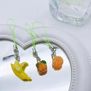 Close-up of cute resin fruit charms with banana and orange shapes on heart mirror