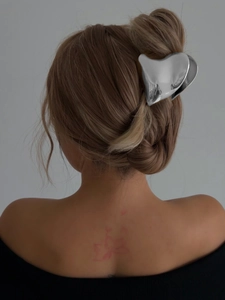Detailed view of silver heart-shaped metal hair claw clip worn on a sleek bun hairstyle