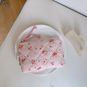 Detail of pink quilted floral fabric storage pouch with zipper and simple wish label