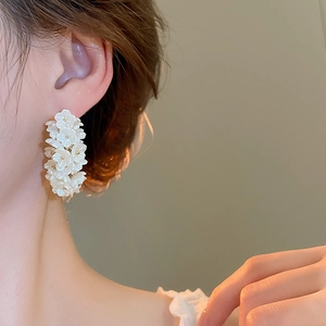 Detailed side view of a model wearing a white pearl cluster flower earring with shell luster