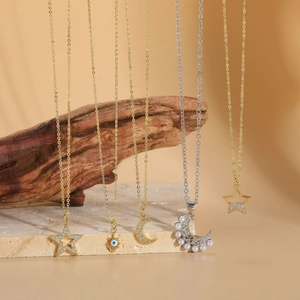 Close-up of luxury star and moon necklaces with pearls and zircons on a marble surface