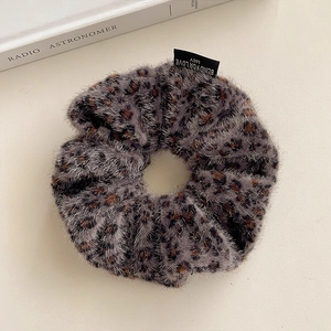 Detail shot of plush leopard print scrunchie with textured fabric and small woven label