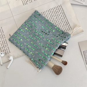 Detail of blue sequin denim drawstring bag with cosmetic items on newspaper