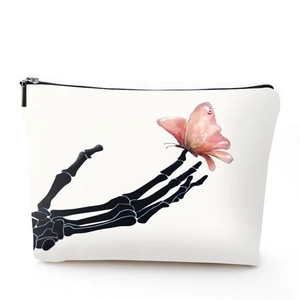 Detailed shot of white linen makeup bag with black zipper and pink butterfly skull print