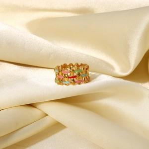 Detail of 18K gold plated woven ring with colorful enamel inlay on silk background