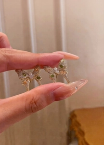 Detailed view of bow-shaped butterfly earrings with green and orange cubic zirconia stones