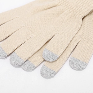 Macro shot of knitted beige touchscreen gloves showing grey fingertip detail and soft texture
