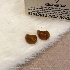 Detail of amber tortoiseshell earrings with resin texture on white faux fur background
