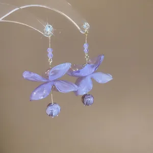 Floral dangle earrings with purple petals and zircon studs on acrylic display
