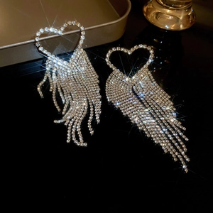Detail of silver heart-shaped fan earrings featuring long rhinestone tassels for a glam look