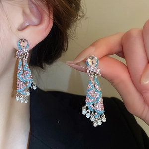 Detail of silver tassel earrings with pink and blue rhinestones on a female model