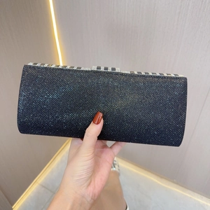 Macro detail of black sequined evening clutch bag with sparkling rhinestone top trim