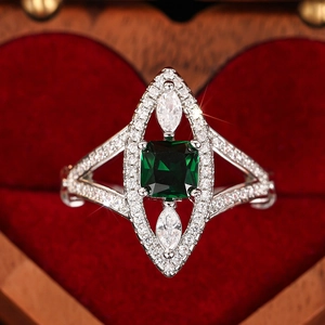 Macro shot of a vintage emerald-cut green gemstone ring in a heart-shaped red velvet box