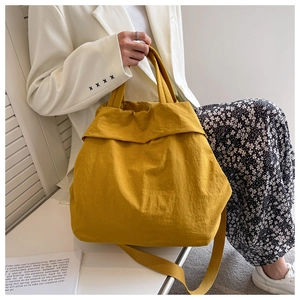 Lifestyle view of a large yellow nylon tote bag paired with a stylish casual outfit