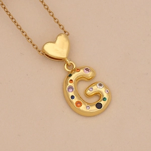 Detailed shot of golden letter G pendant with colorful cubic zirconia and heart link