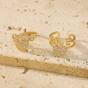 Elegant gold heart and LOVE ear cuffs with cubic zirconia on natural stone surface