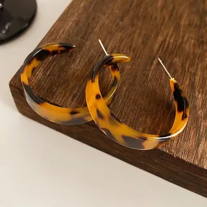 Retro leopard print acetate hoop earrings with silver pins on a wooden display block
