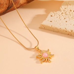 Detail of golden sun pendant with pink opal stone and zircons on snake chain
