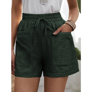 Detail of high-waisted dark green linen shorts showing drawstring and pocket texture