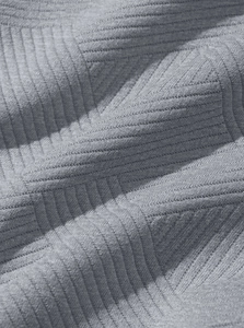 Gros plan de la texture en maille côtelée gris clair montrant la souplesse du tissu