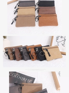 Close-up of colorful canvas coin purses with zippers and metal keychains on a white cloth