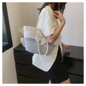 Detail of white woven tote bag with knotted handles and a delicate bow decoration