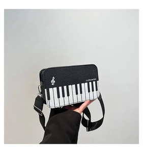 Detail of hand-held piano key crossbody bag with treble clef and music text
