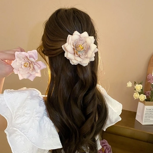 Detail of two pink silk rose hair clips shown on wavy hair and as a product close-up