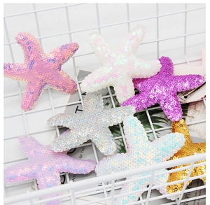 Detail of colorful sequined starfish hair clips in pink, purple and silver tones