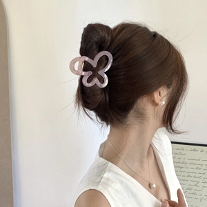 Detail of translucent pink-purple butterfly hair claw clip shown on a high bun hairstyle
