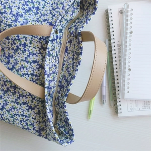 Detailed view of Klein Blue floral tote bag with zipper and light brown handle