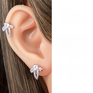 Detail macro view of sparkling silver bow earrings with micro-set cubic zirconia on ear