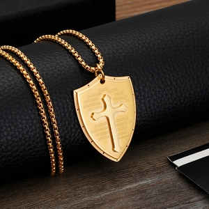 Close-up of golden shield pendant with embossed cross and engraved Bible verse details