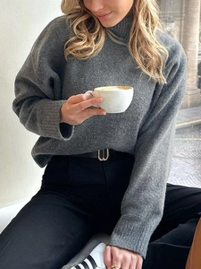 Pull à col roulé gris foncé coupe ample porté dans un café pour un look décontracté d'hiver