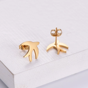 Pair of vintage gold swallow bird stud earrings with a brushed metal texture on a white block