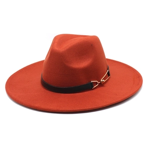Detail of brick red wool fedora hat featuring a black band and gold pin accent