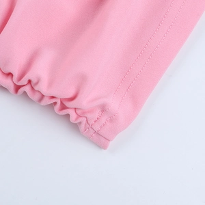 Détail d'une robe rose à manches longues montrant des coutures fines et un tissu texturé