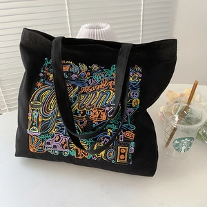 Close-up of colorful graffiti embroidery and high-density canvas texture on black tote bag