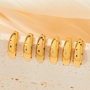 Bagues larges dorées avec pierres de zircone colorées sur une surface en pierre