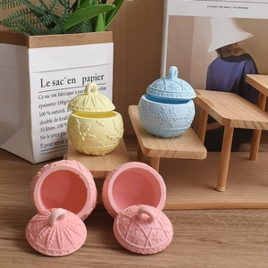 Pastel relief candle jars with snowflake leaf patterns and ring handles on wood shelves